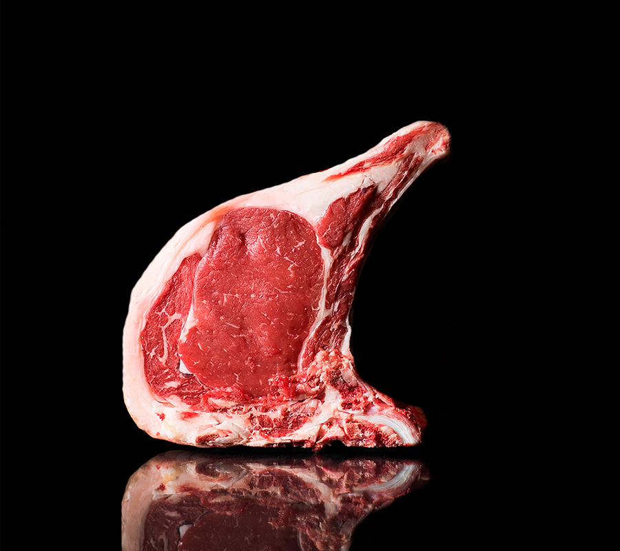 Chuletón de ternera Bruna del Pirineo, pieza de lomo alto con hueso y grasa exterior blanca, sobre fondo negro